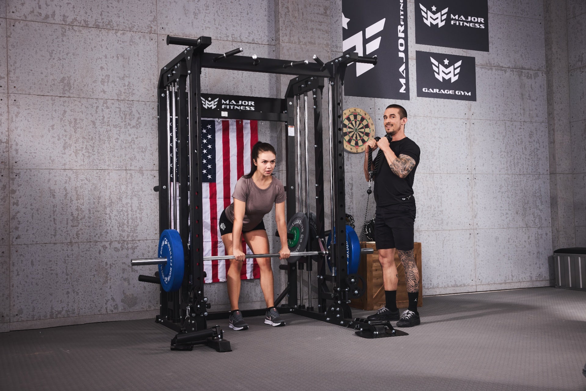 Female athlete doing a barbell deadlift under the guidance of a personal trainer in a home gym equipped with Major Fitness gear.