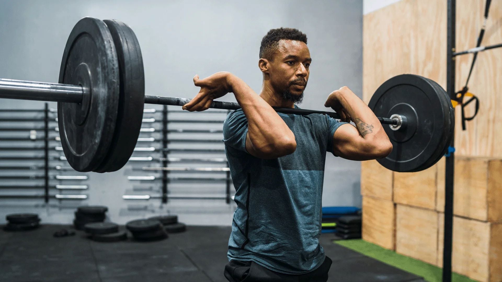  A man performing a barbell front squat as part of strength training in a gym.