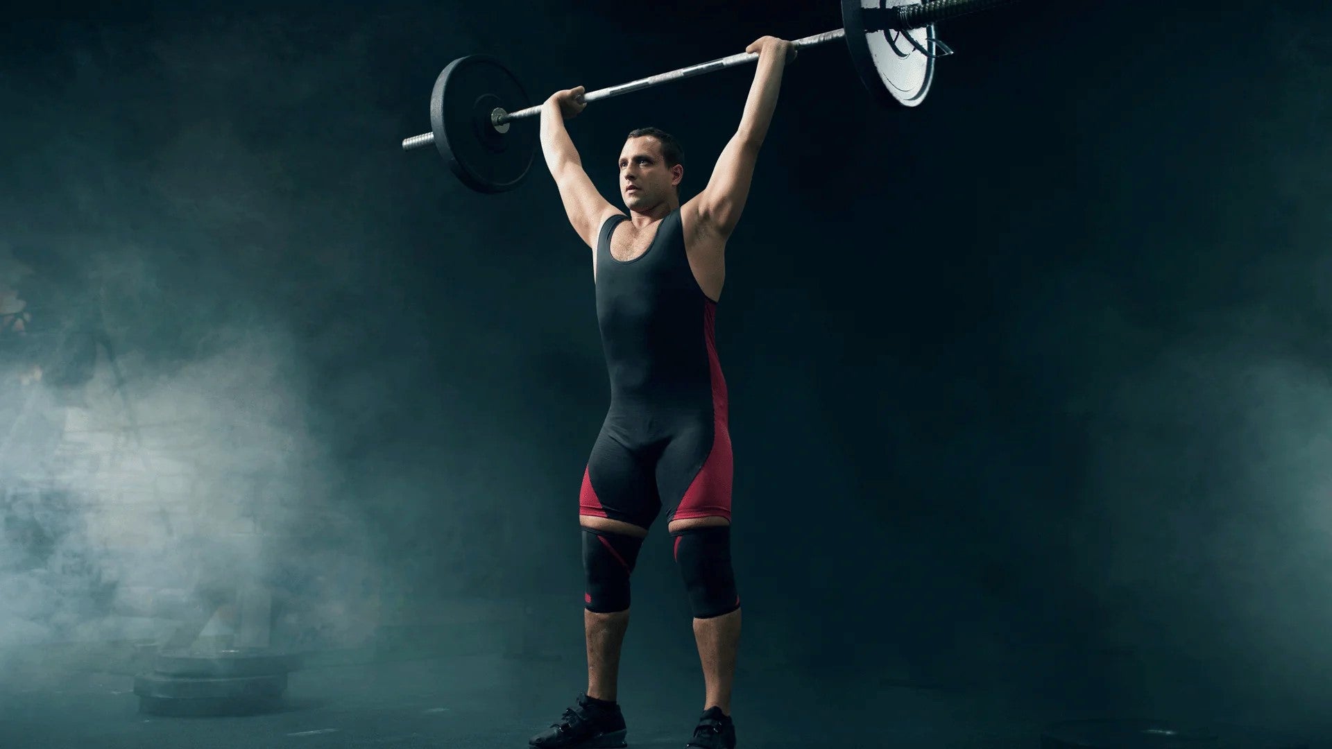 Male weightlifter performing an overhead press with a barbell during a competition.