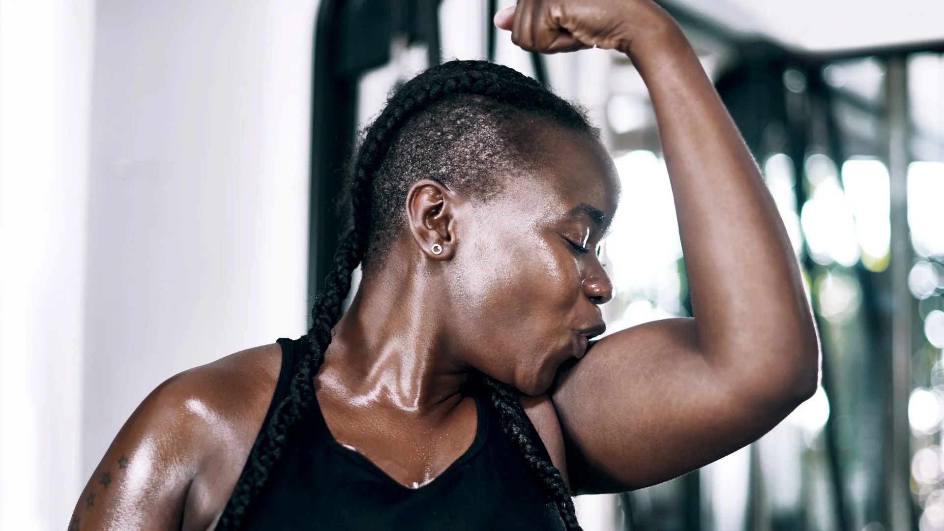 woman celebrating her muscle growth by flexing her bicep after home workout