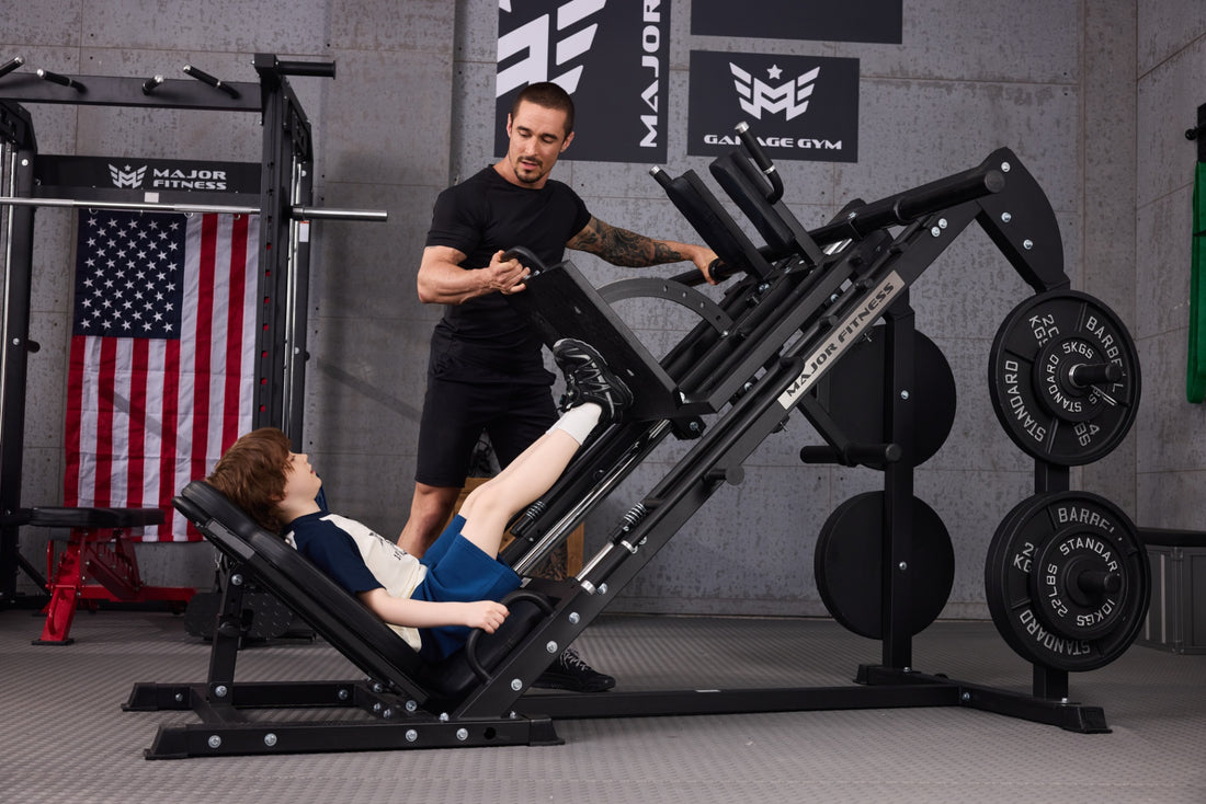 Child doing a leg press exercise with the assistance of a trainer in a gym setting.