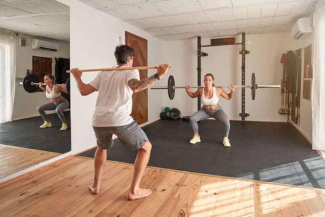 Man and woman performing barbell squats in a home gym setup.