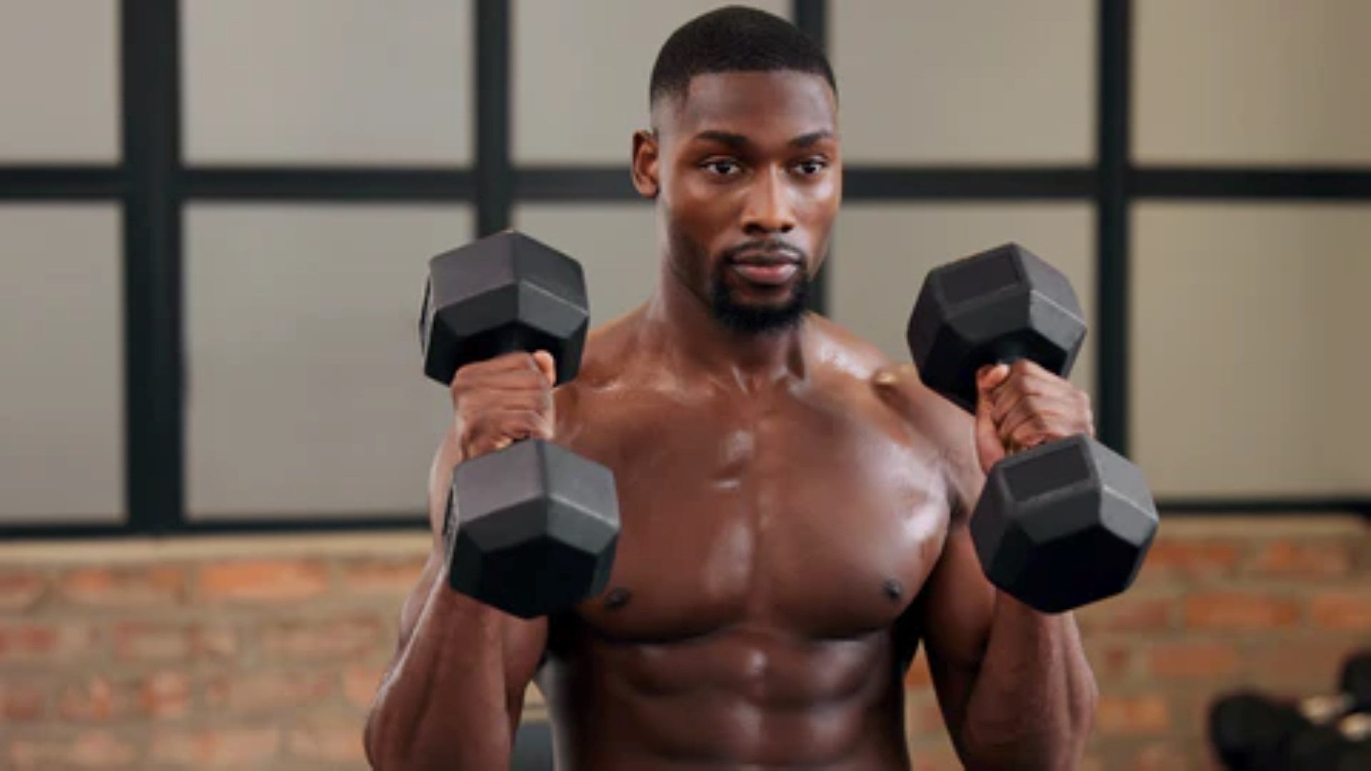 A man performing a dumbbell bicep curl as part of his strength training routine in a home gym.