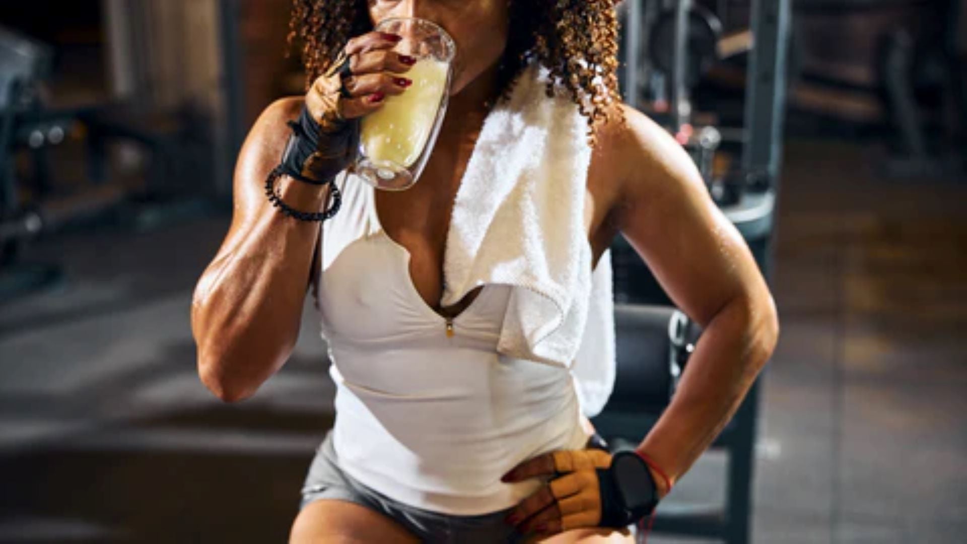 Person drinking a hydration beverage after a workout session in the gym.