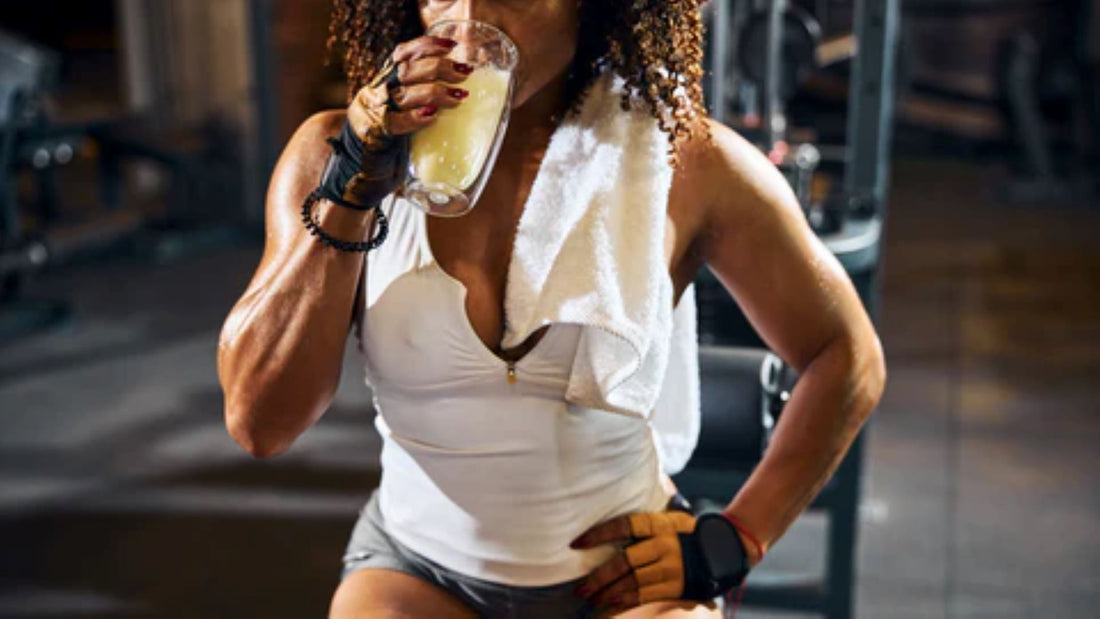 Person drinking a hydration beverage after a workout session in the gym.