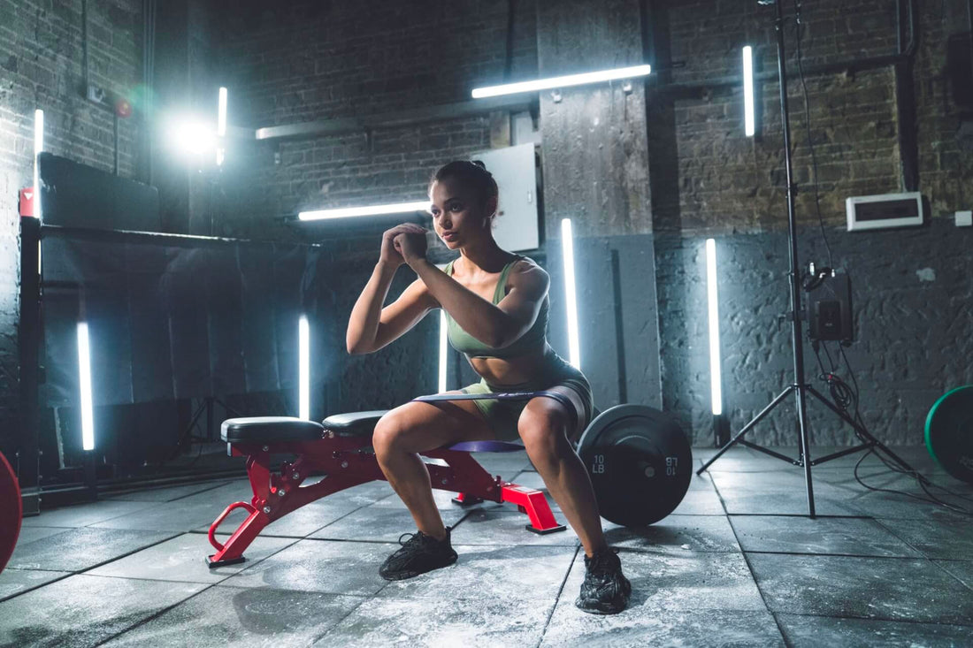 Woman performing a squat exercise using a weight bench in a gym.