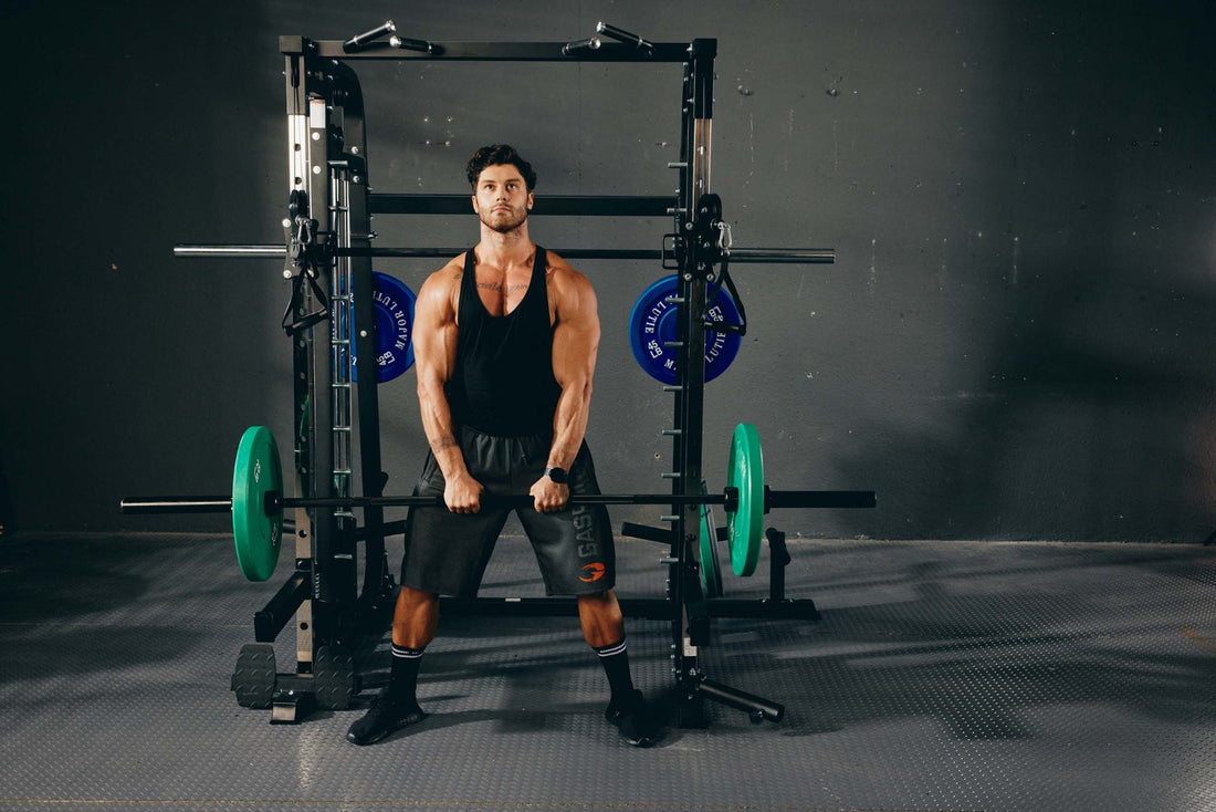 Fitness enthusiast lifting a barbell for a deadlift workout with a smith machine in a gym environment.