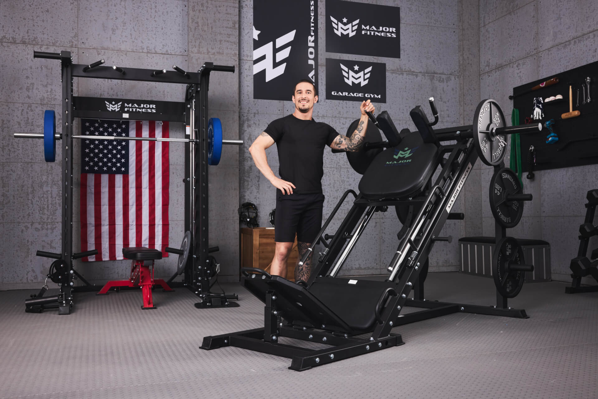 Man standing beside Major Fitness smith machine and hack squat machine in a home gym setup