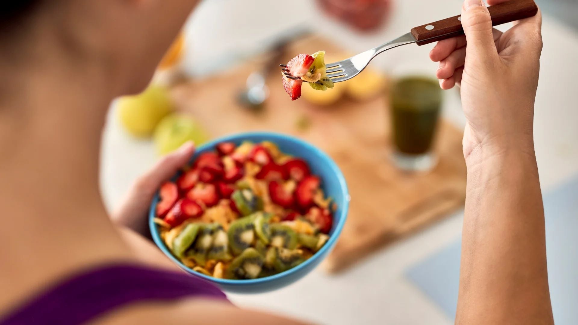 A person eating a bowl of fresh fruits, emphasizing a nutritious breakfast for energy and wellness.