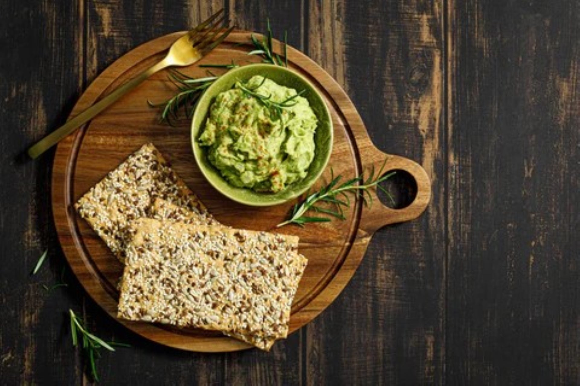 healthy crackers served with avocado dip on a wooden board.