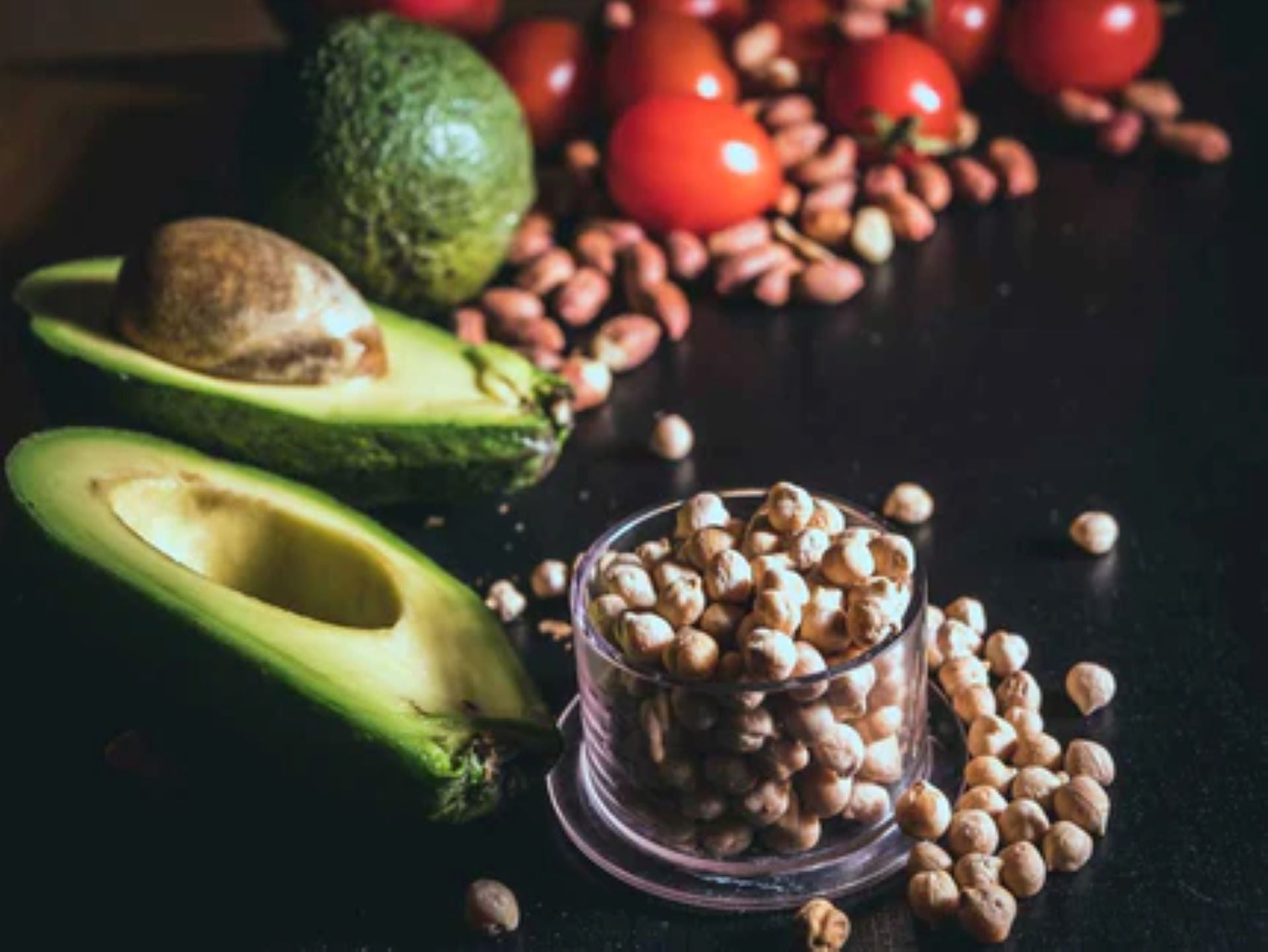 A plant-based food setup with avocados, chickpeas, and cherry tomatoes, ideal for bodybuilders.