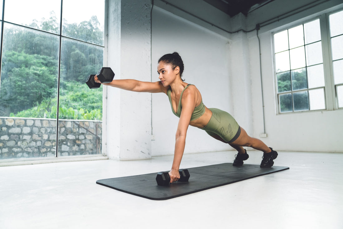 Core workout with a dumbbell plank shoulder tap by a female athlete.