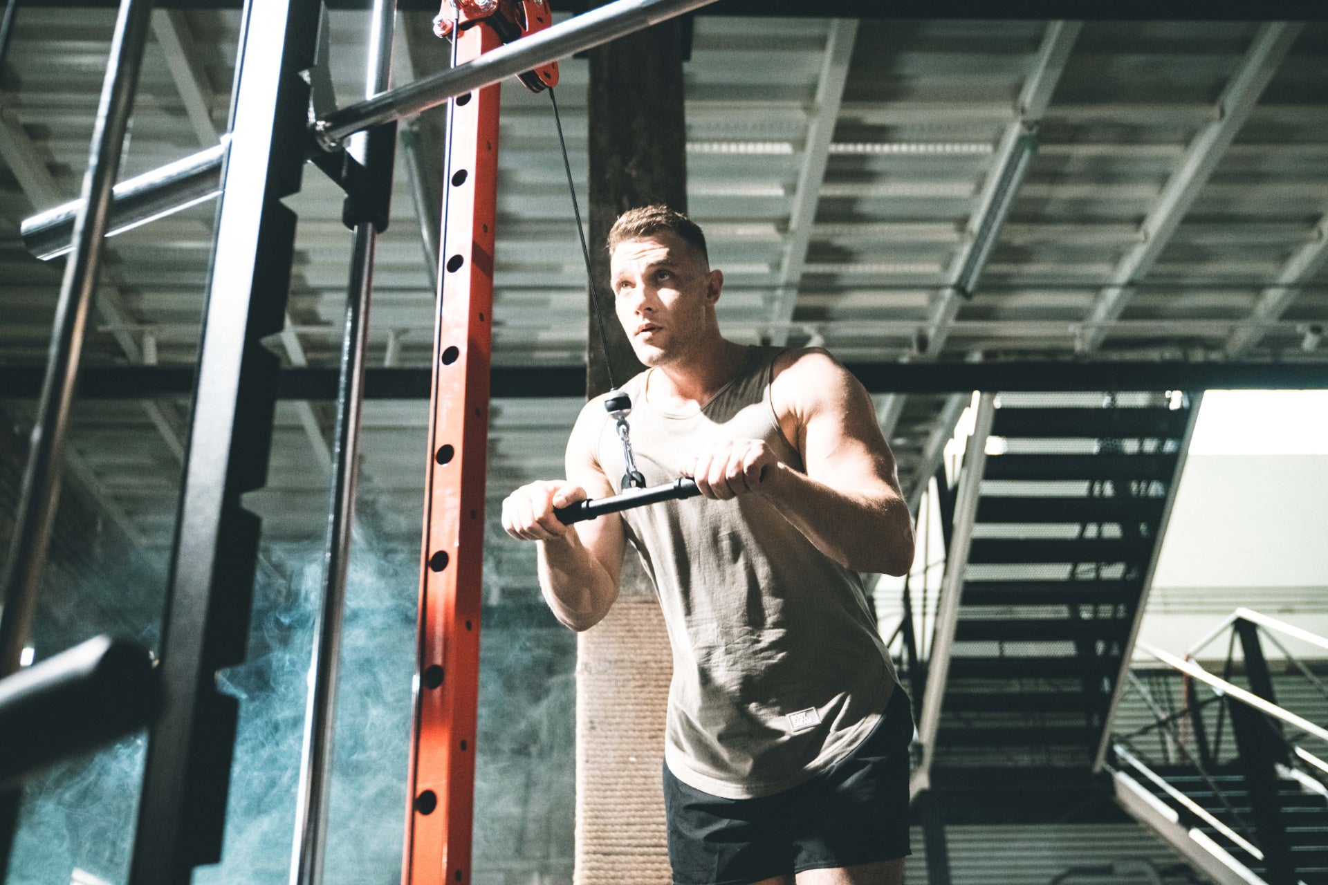 Man performing a workout on a cable machine in a home gym.