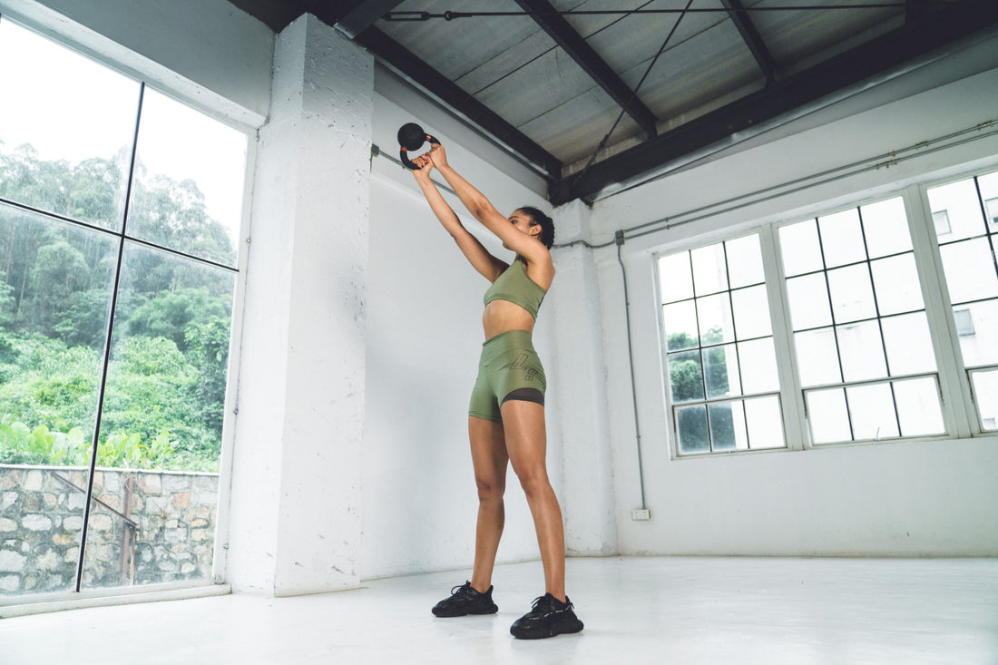 Woman performing a kettlebell deadlift in a home workout setting.