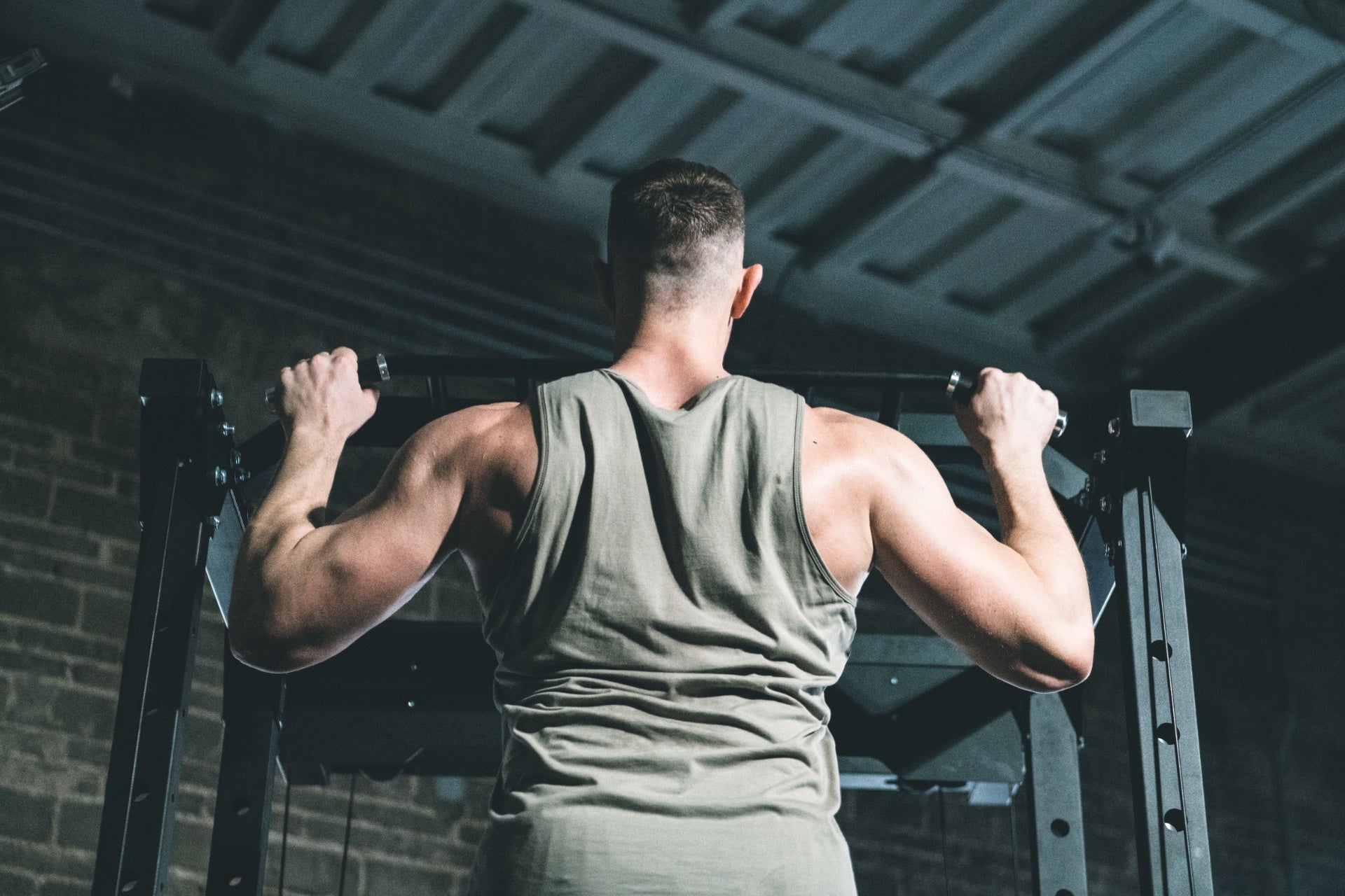 Man performing pull-ups on a bar for back strength training in a gym.