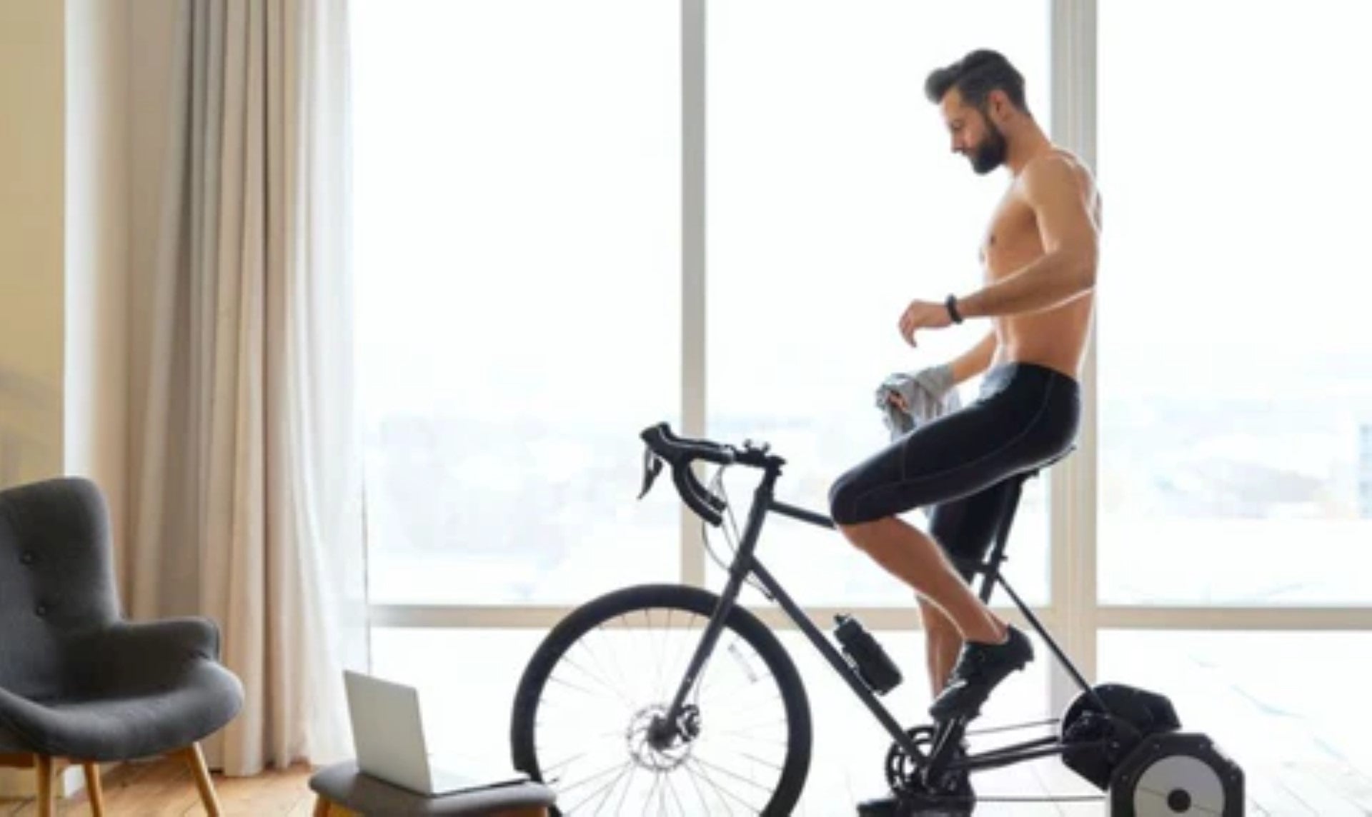 Man using an indoor cycling trainer for a workout at home.