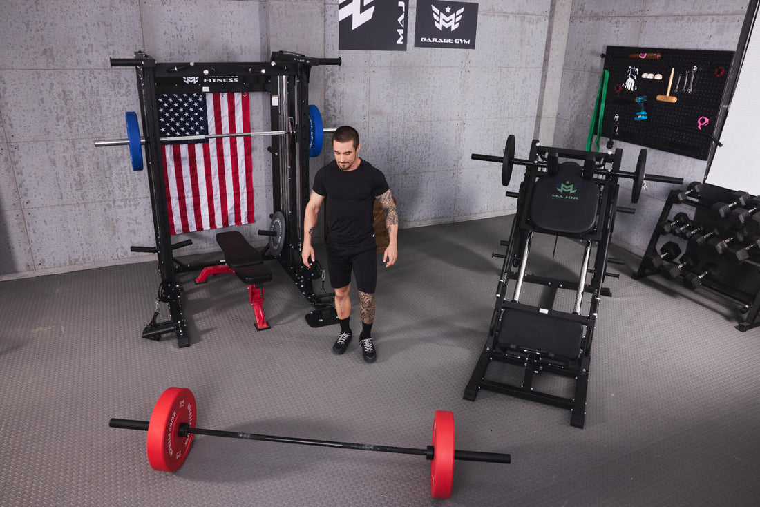 A small home gym includes a wall-mounted tool organizer, free weight dumbbells, leg press machine, and a smith machine