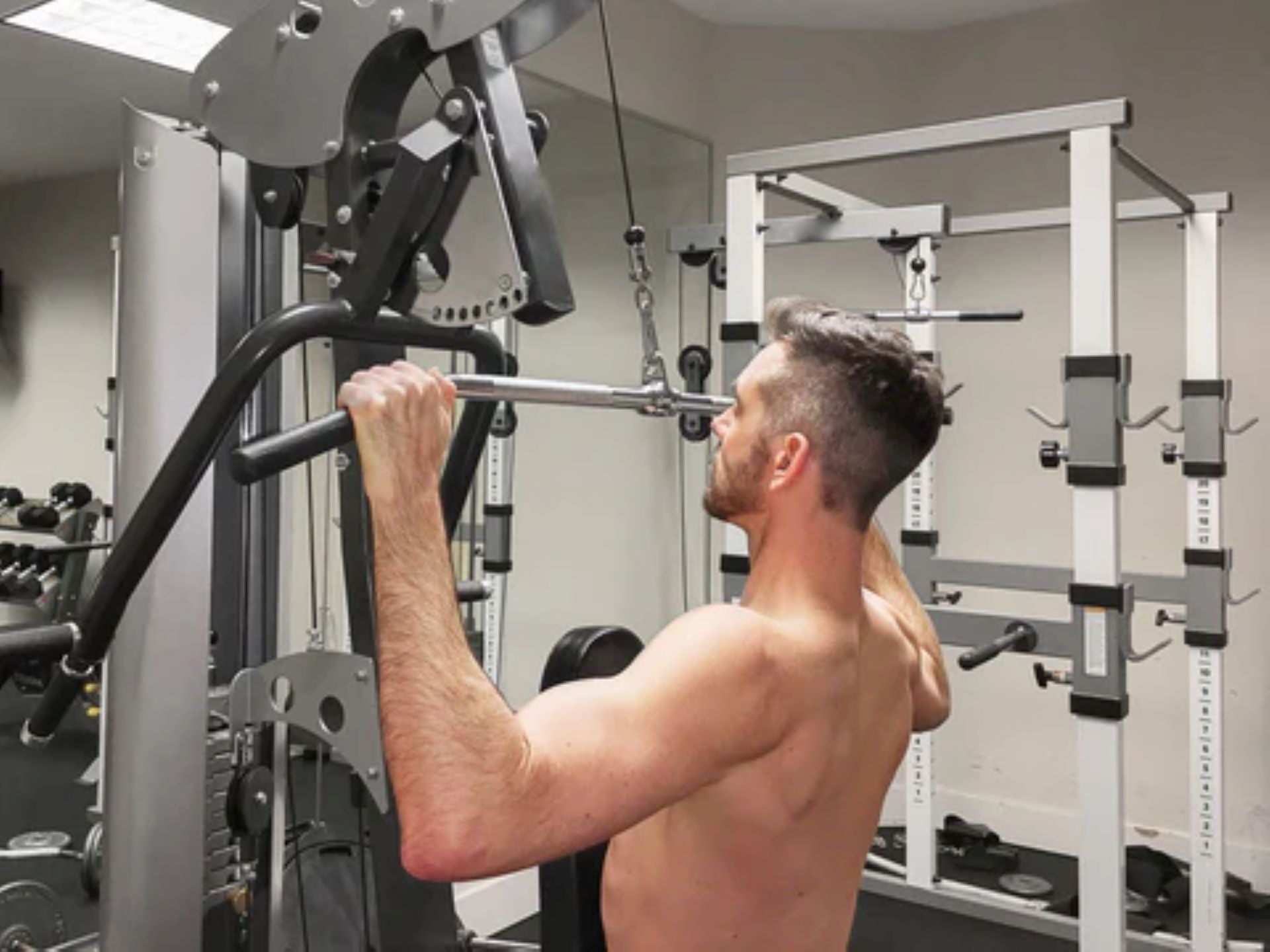 Man exercising with a lat pulldown machine in a gym setting.