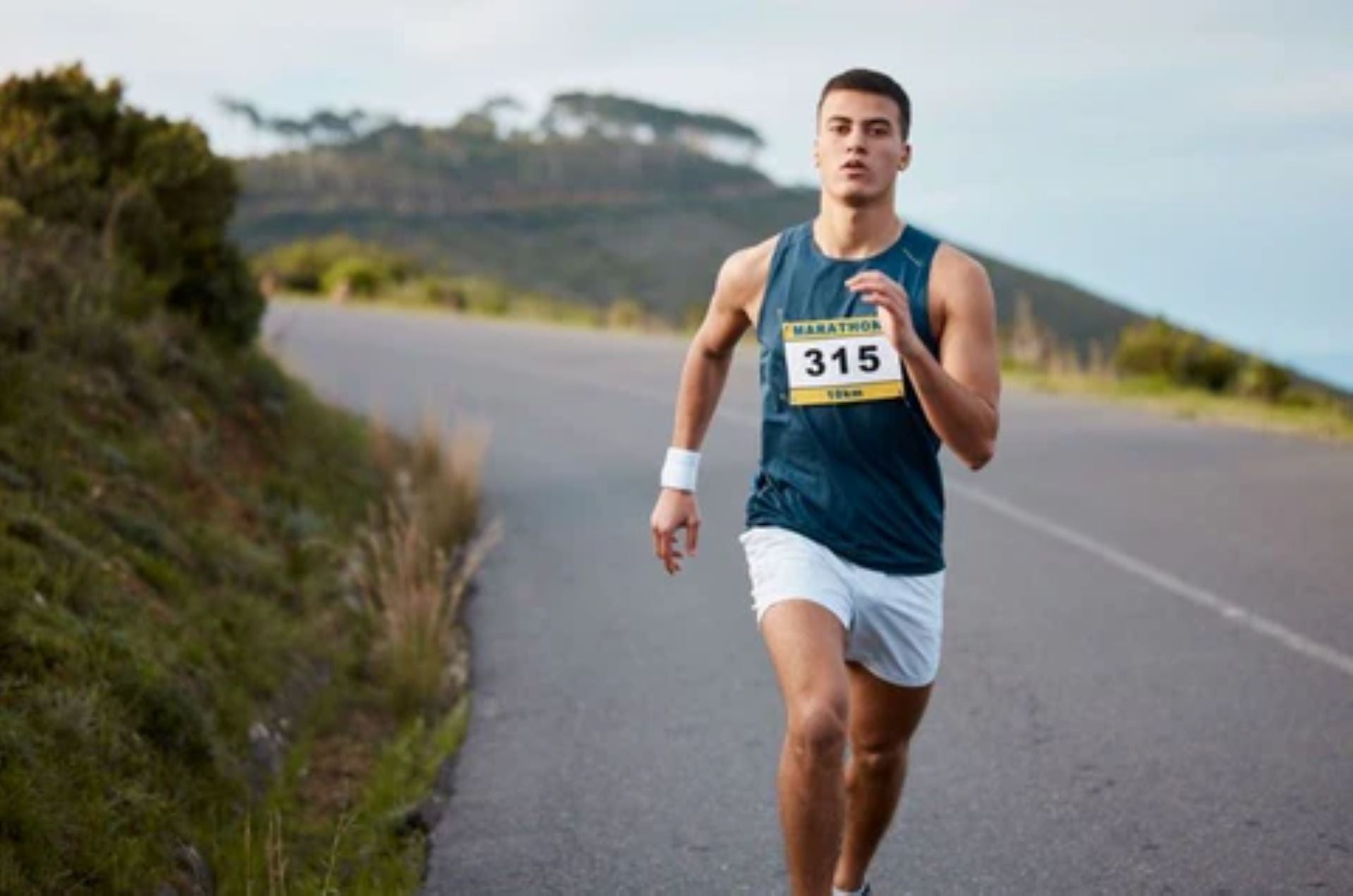 Male marathon runner training on an open road, focusing on endurance and speed.