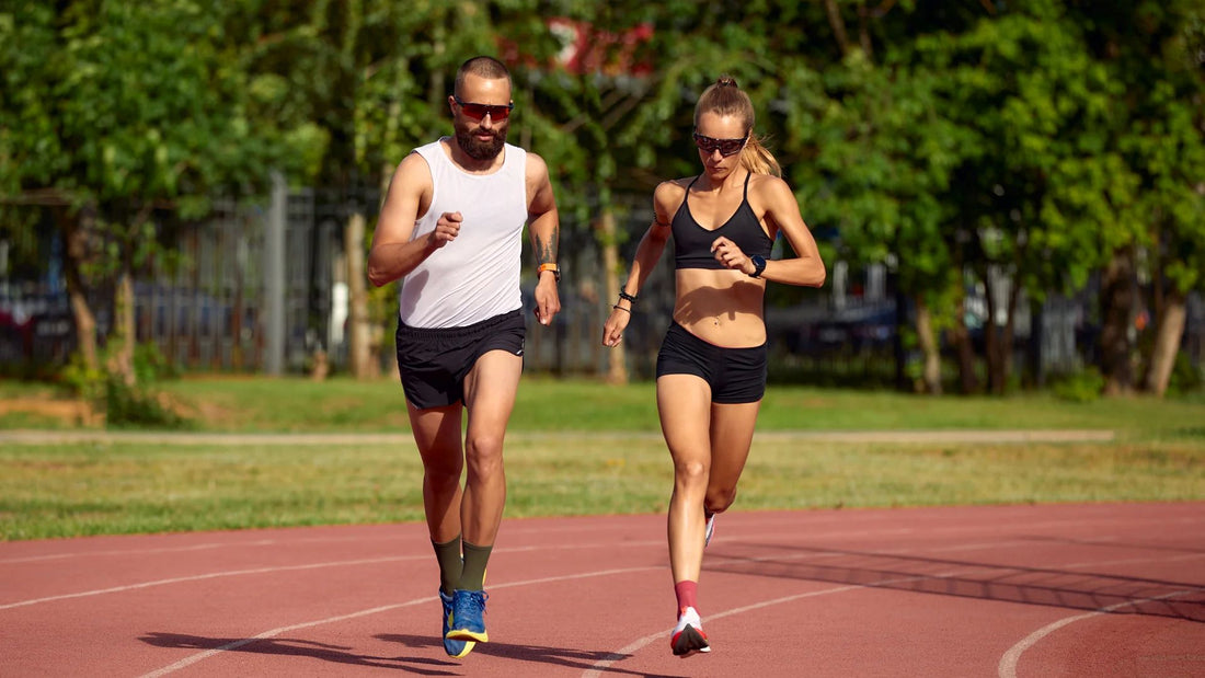 A man and a woman running together on a track, focusing on outdoor cardio exercise for improved fitness and endurance.