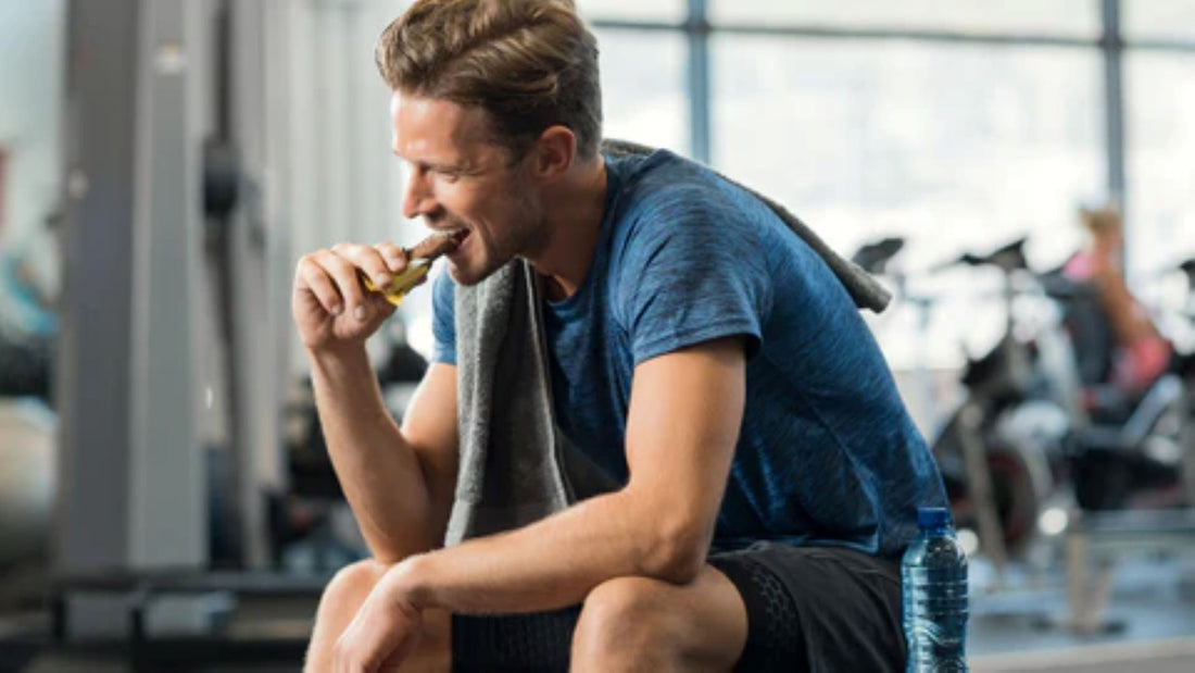 Man enjoying a protein bar after a workout session in the gym, aiding recovery.