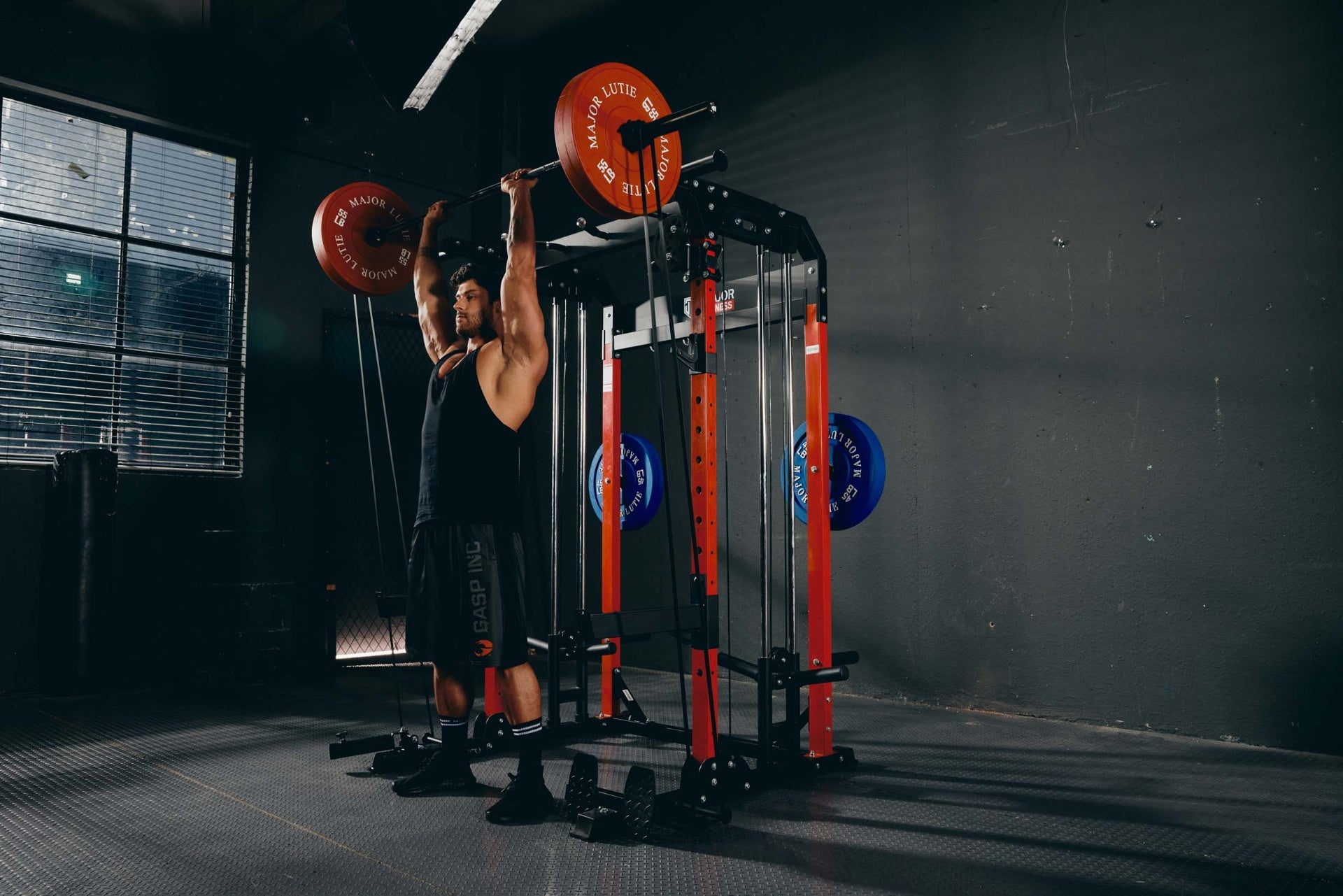 Man performing an overhead press using a barbell on a power rack during strength training.