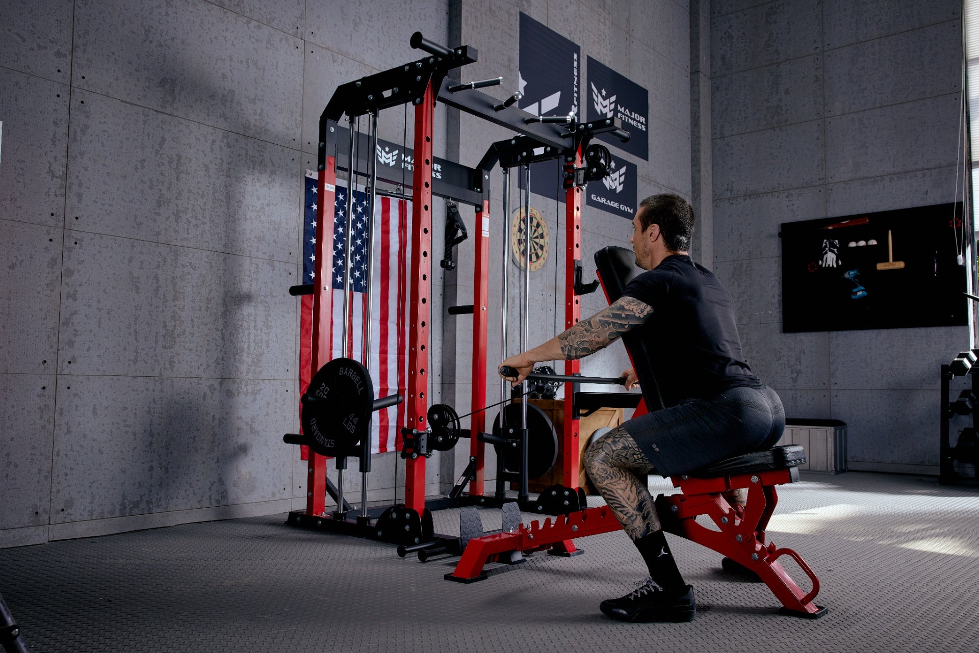 Man performing a seated cable row exercise in a home gym with a red power rack.