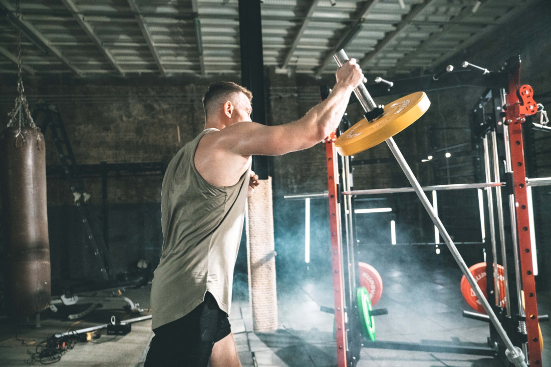 Man executing a strength training landmine press with a barbell in the gym.