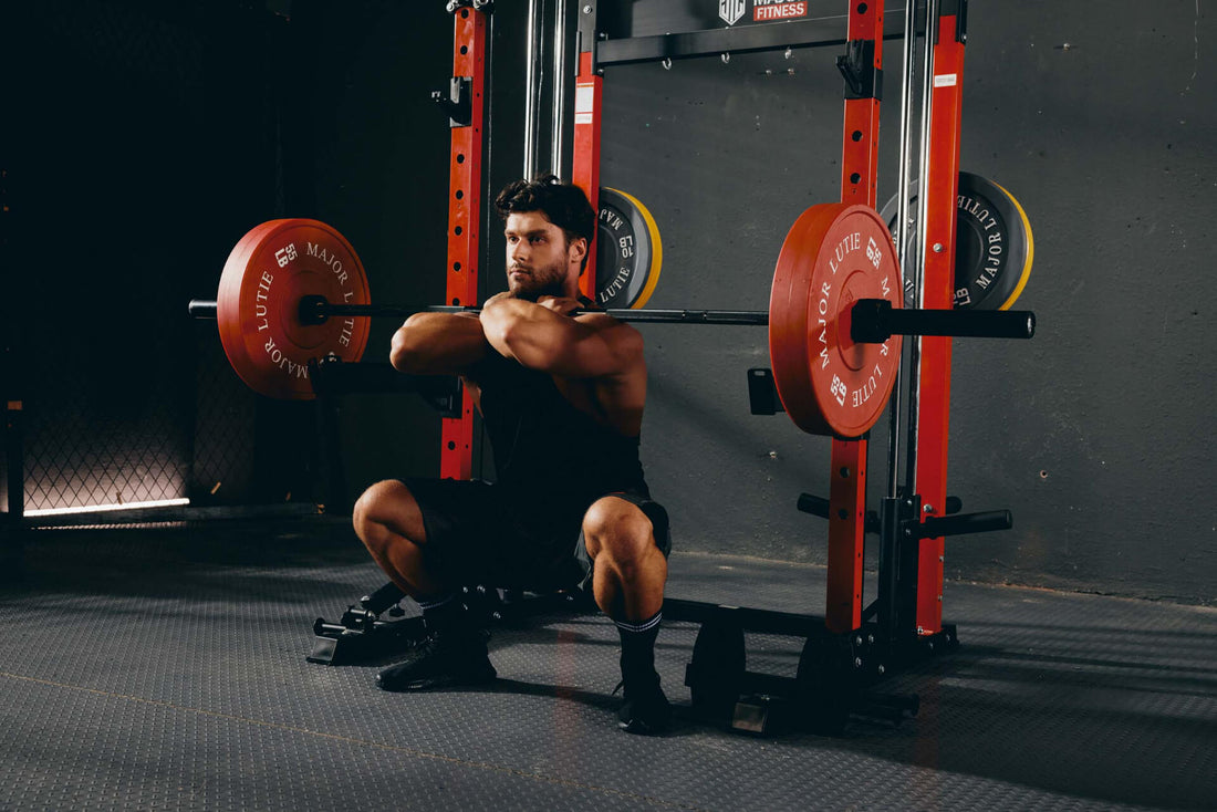 Male athlete executing front squats using a power rack in a fitness center.