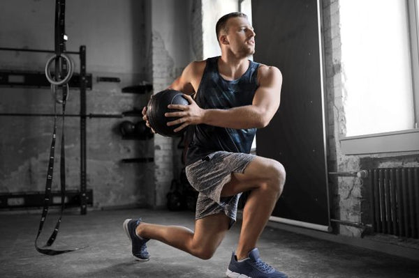 Home workout featuring a man using a medicine ball for a lunge exercise